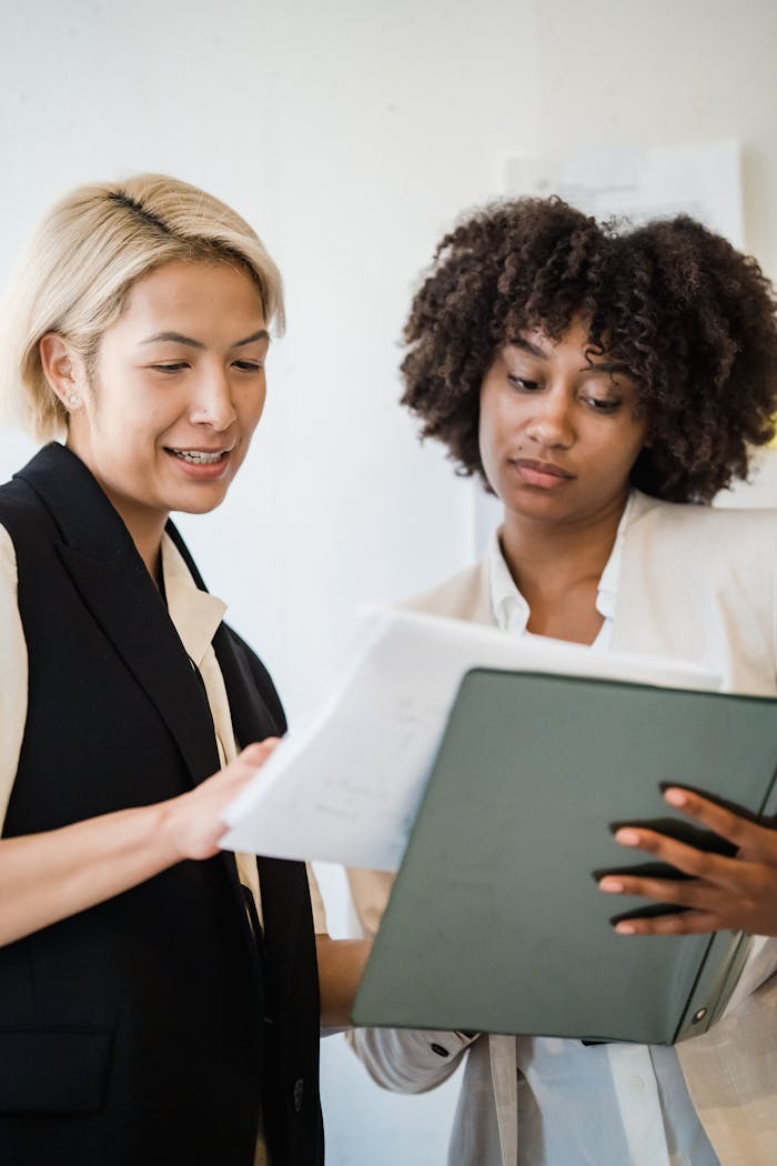 Two women engaging in a business meeting, reviewing documents and collaborating on a project.