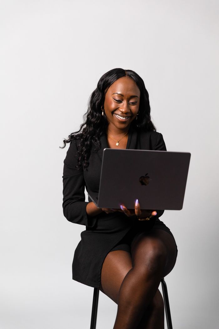 Smiling businesswoman in formal attire working on her laptop with focus and determination.